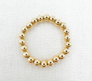 Gold beaded ring on a white textured background