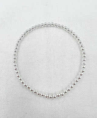 Silver beaded bracelet on a textured white background