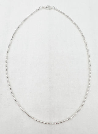 Silver necklace on a light gray background