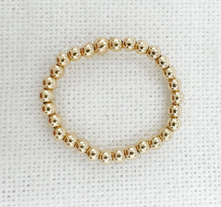 Gold beaded ring on a white textured background
