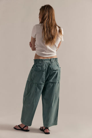 Person wearing a white top and green pants on a beige background