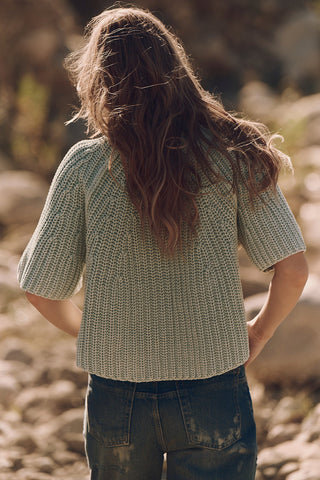 Person wearing a textured green shirt standing outdoors with a blurred natural background