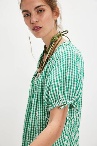 Woman wearing a green and white checkered shirt with a scarf on a white background
