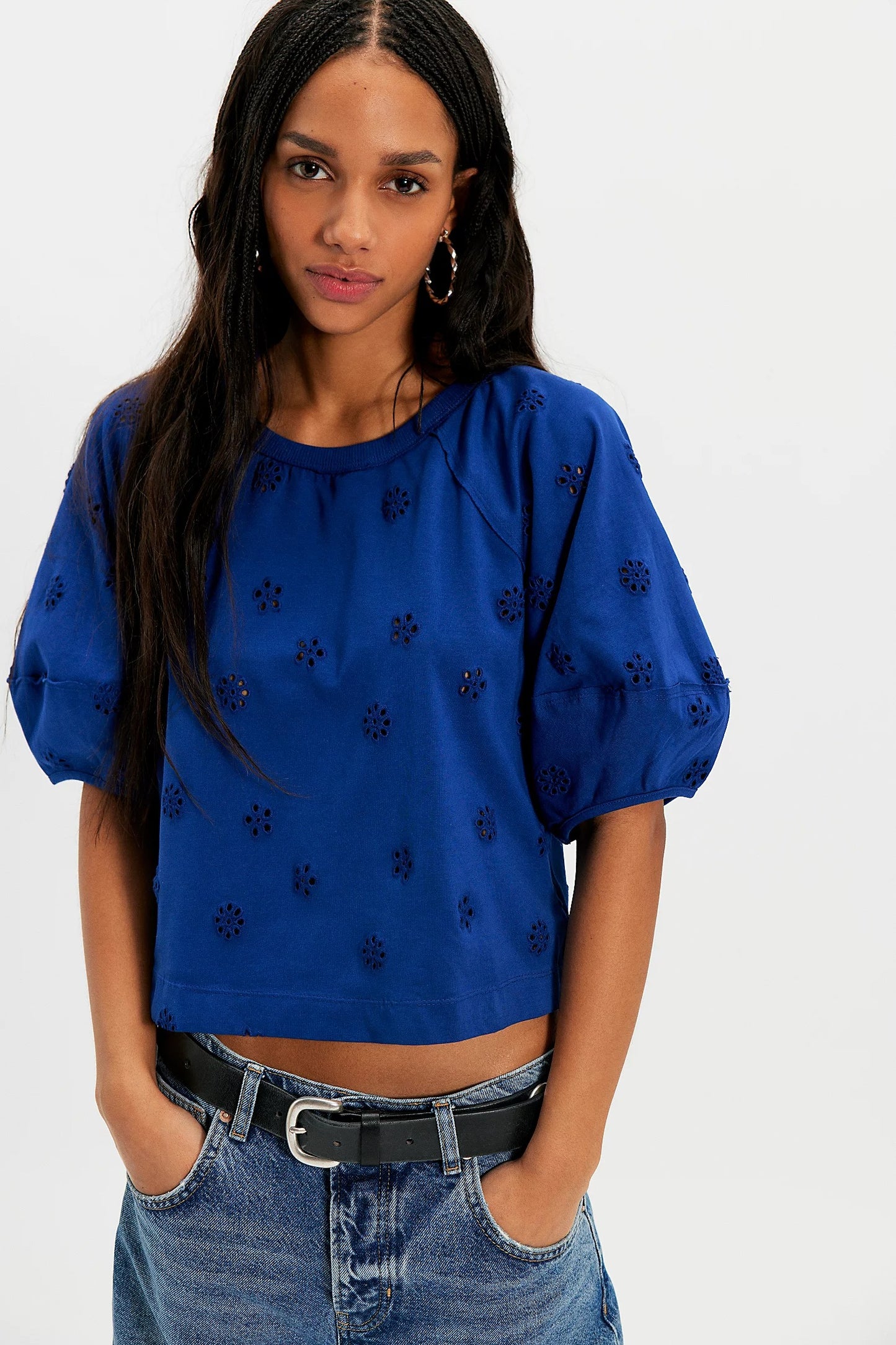 Woman wearing a blue top with black patterns and jeans on a white background