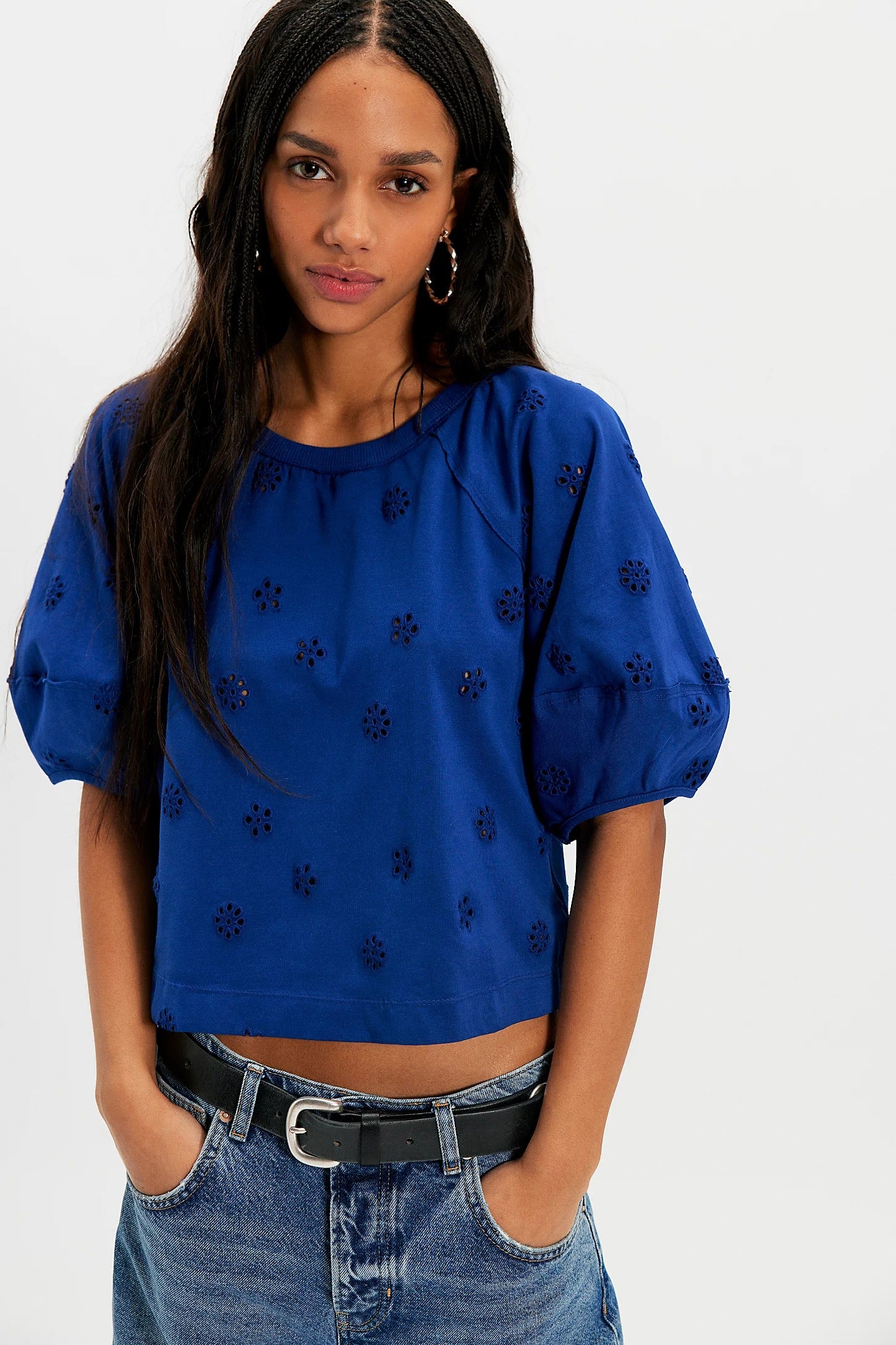 Woman wearing a blue top with black patterns and jeans on a white background
