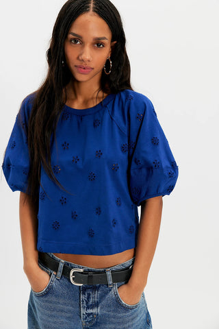 Woman wearing a blue top with black patterns and jeans on a white background