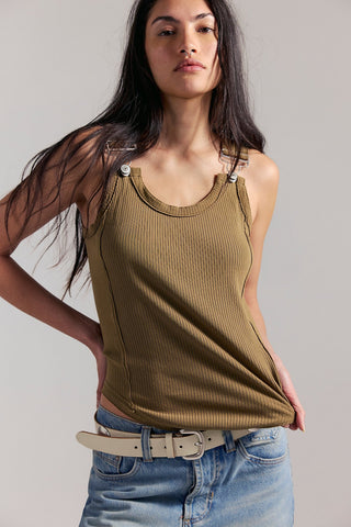 Woman wearing a ribbed tank top and jeans against a plain background
