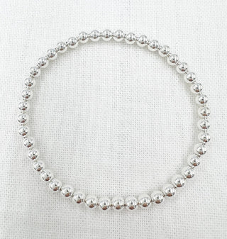 Silver beaded bracelet on a textured white background