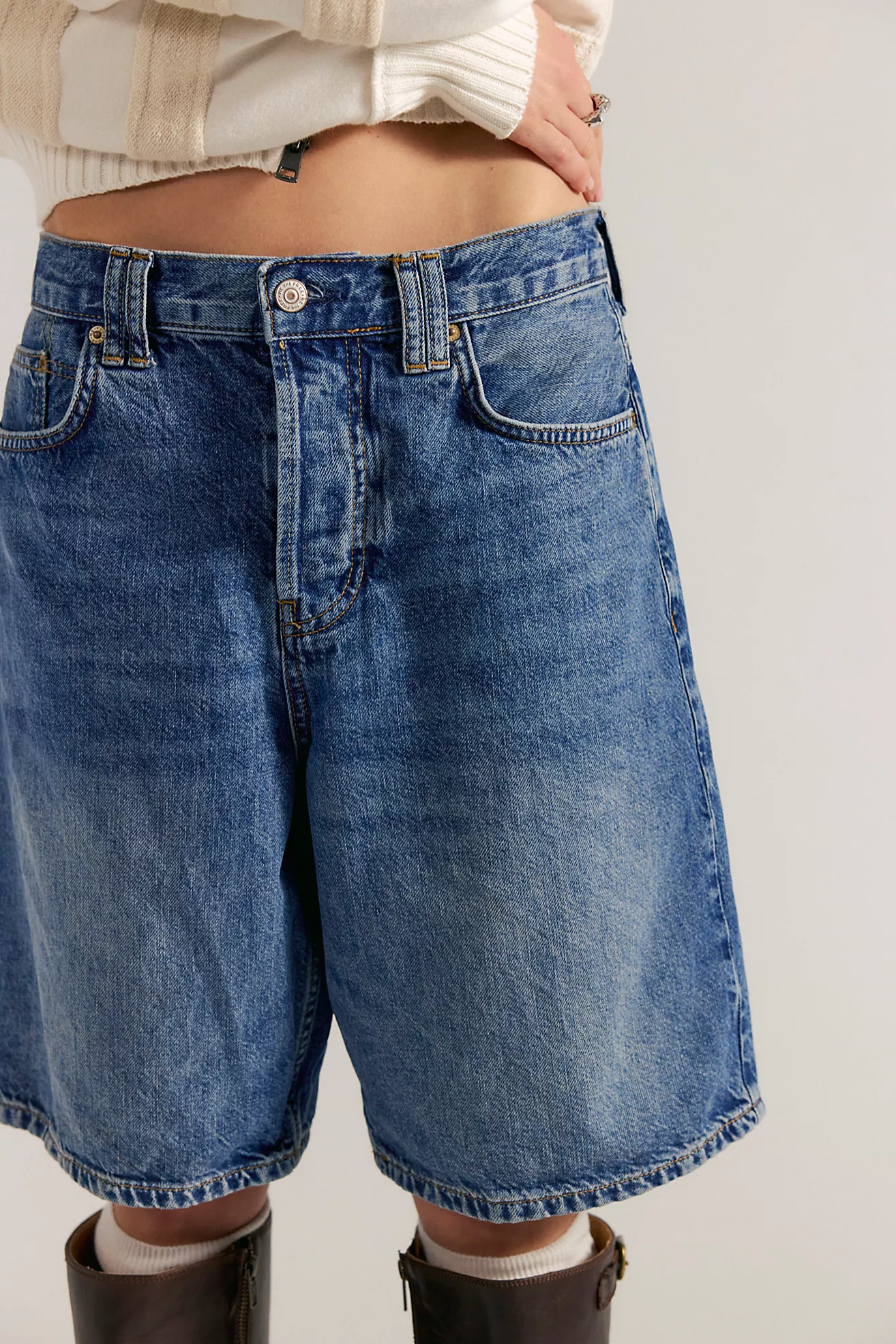 Person wearing blue denim shorts on a plain background