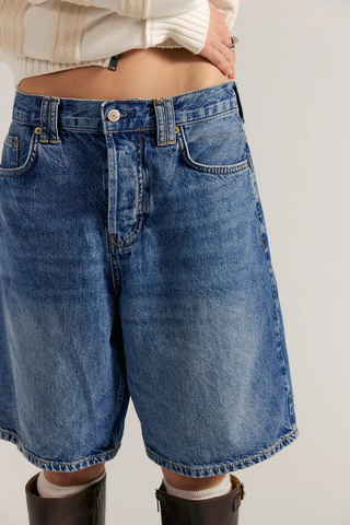 Person wearing blue denim shorts on a plain background