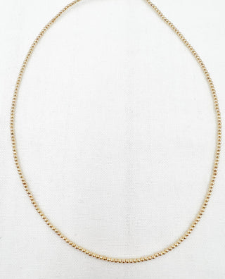 gold necklace on a light grey background