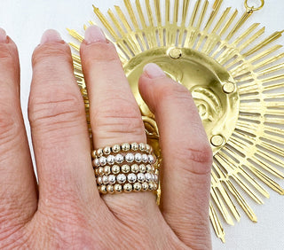 women wearing gold and silver beaded rings stack on her ring finger