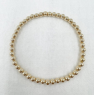 Gold beaded necklace on a white fabric background