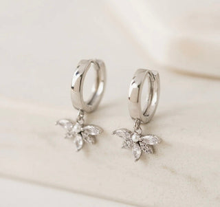 Silver hoop earrings with butterfly charms on a light background