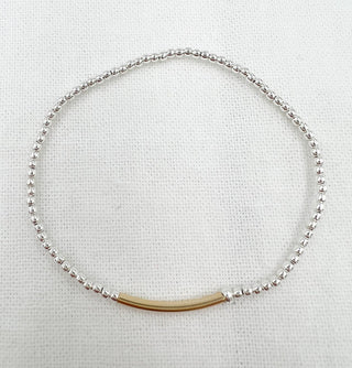 Silver beaded bracelet with a gold bar on a light gray background