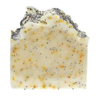 Bar of soap with visible poppy seeds and tea tree oil droplets, branded as Buck Naked Soap Company.