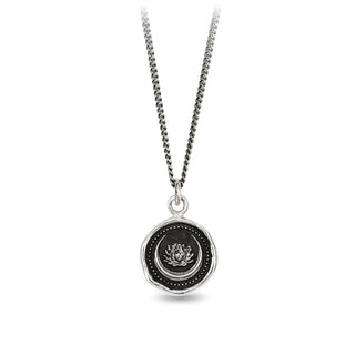 A sterling silver necklace featuring a circular black and silver talisman with a lotus flower design, fastened with a sterling silver chain and a sterling silver Pyrrha branded quality tag.