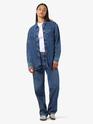 Person wearing a blue denim jacket and jeans on a white background