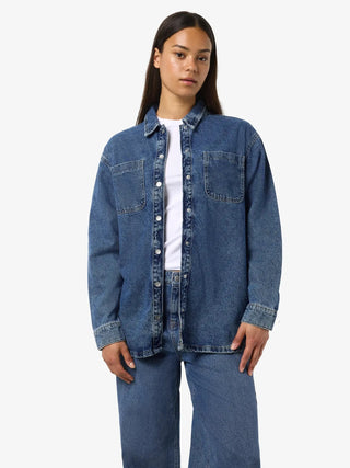 Person wearing a blue denim jacket and jeans on a white background