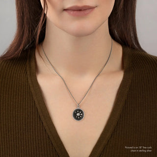 Person wearing a necklace with a pendant on a plain background