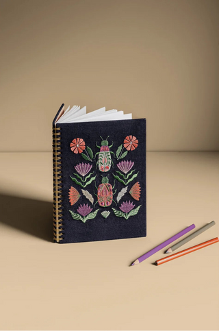 Notebook with floral and beetle design on a beige background
