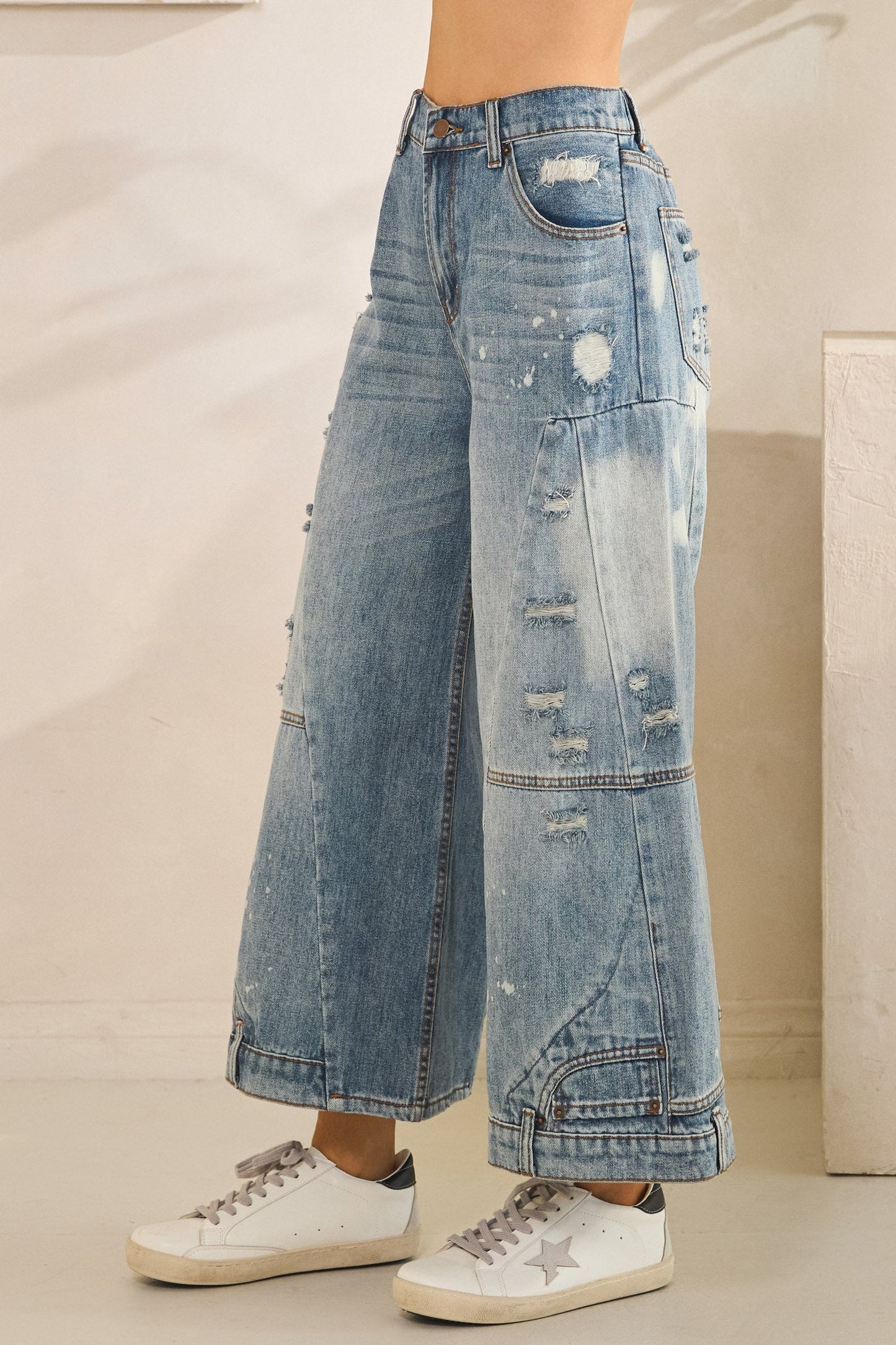 Wide-leg distressed jeans worn by a person on a neutral background