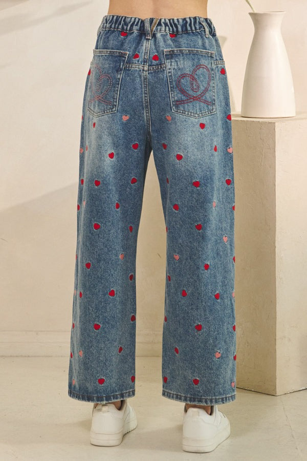 Blue jeans with red polka dot pattern on a neutral background