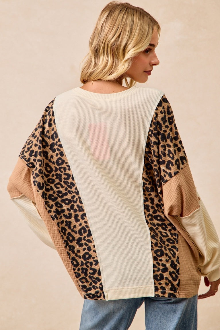 Woman wearing a sweater with leopard print and beige panels on a beige background