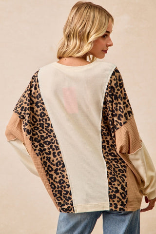 Woman wearing a sweater with leopard print and beige panels on a beige background