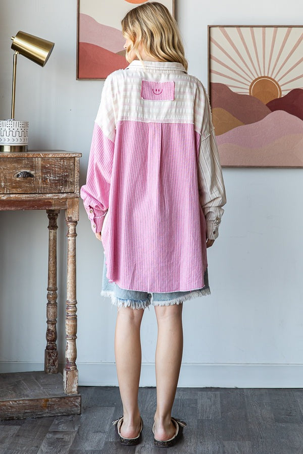 Person wearing a pink and white shirt in a room with abstract art on the wall.