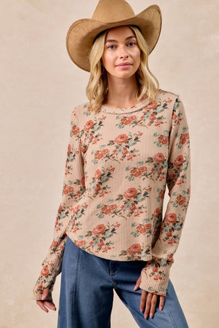 Woman wearing a floral blouse and cowboy hat against a beige background