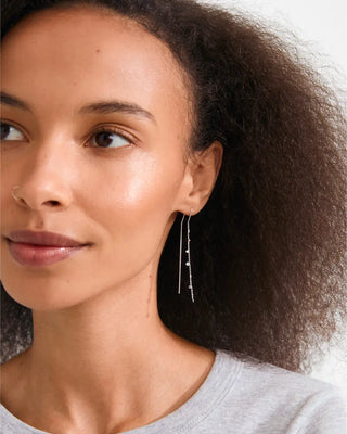 Close-up of a woman wearing silver earrings with a neutral background