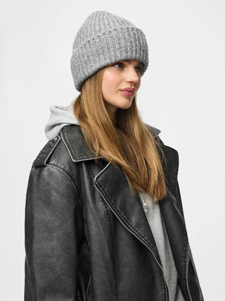 Woman wearing a gray beanie and black leather jacket on a light gray background