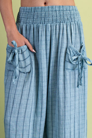 Light blue pants with drawstring waist and side pockets on a green background