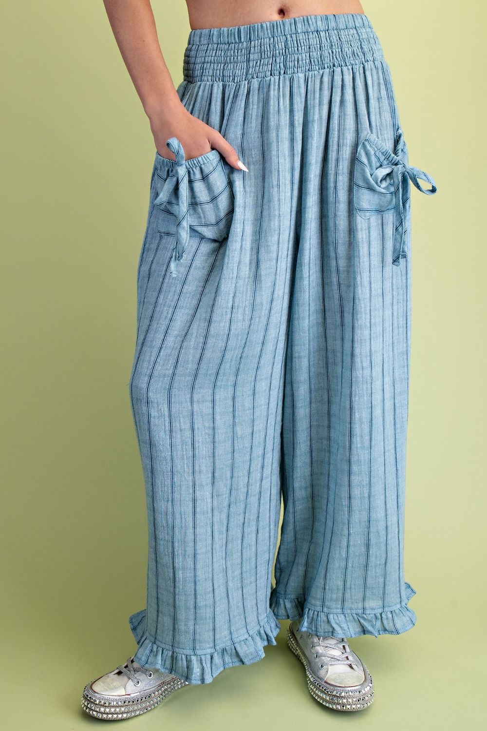 Light blue ribbed pants with ruffled bottom on a green background