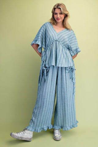 A women wearing a striped blue matching set on a green background. 