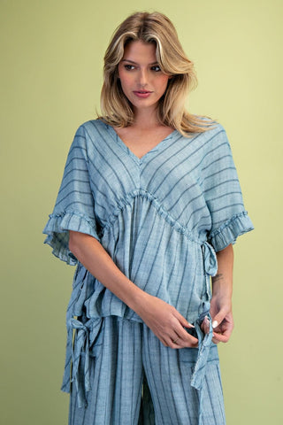 A women wearing a striped blue top on a green background. 
