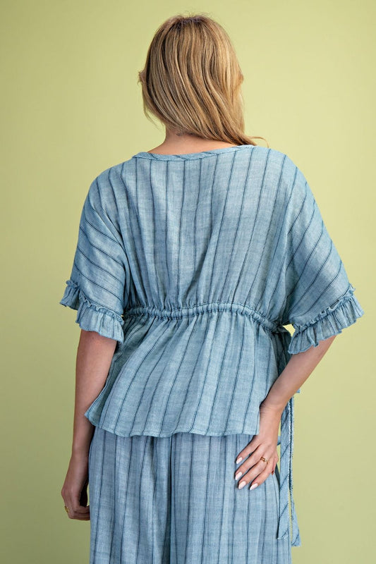 A women wearing a striped blue top on a green background. 