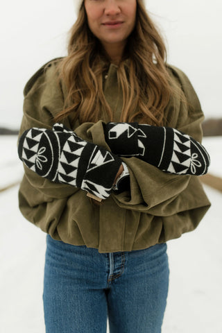 Women wearing a pair of mini tipi mittens standing outside in the snow. 