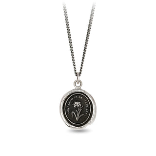 Silver necklace with a round pendant featuring an engraved design on a white background