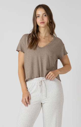 Woman wearing a brown t-shirt and white pants on a plain background