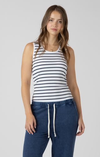 Woman wearing a striped tank top and blue pants on a plain background