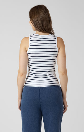 Woman wearing a striped tank top and blue pants on a plain background