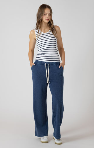 Woman wearing a striped tank top and blue pants on a white background