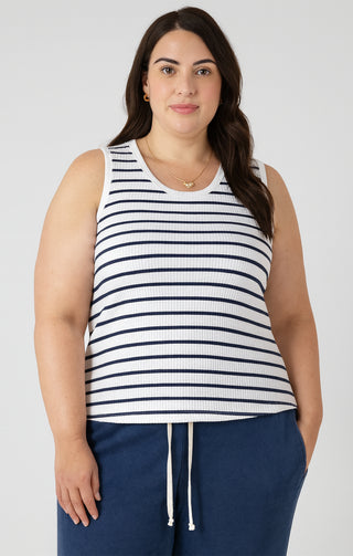 Woman wearing a striped tank top and navy pants against a white background