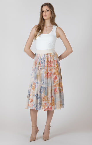 Woman wearing a white top and colorful pleated skirt on a plain background