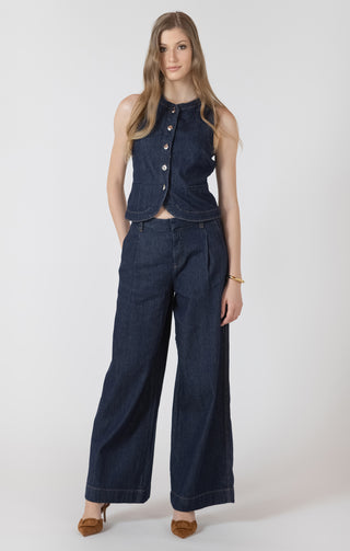 Woman wearing a denim vest and wide-leg jeans on a white background