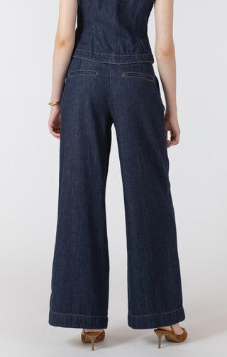 Person wearing a dark denim jumpsuit on a white background