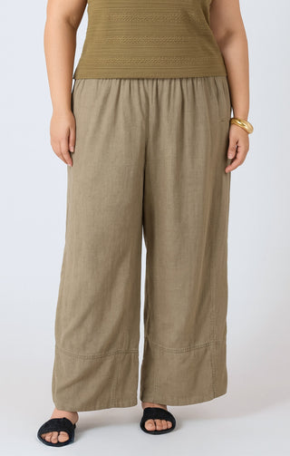 Person wearing a green top and beige wide-leg pants on a white background