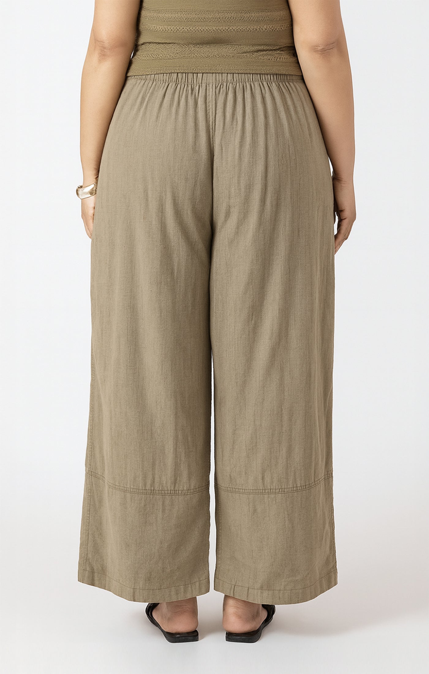 Person wearing beige wide-leg pants on a white background